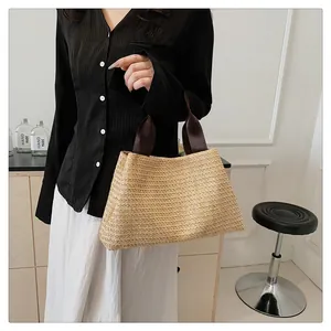 Detailed close-up of handmade straw tote bag with brown handles in natural light