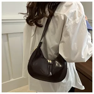 Detail of dark brown glossy leather crescent shoulder bag with dual zipper closure