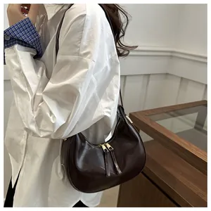 Close-up of glossy dark red crescent shoulder bag on white shirt for daily style
