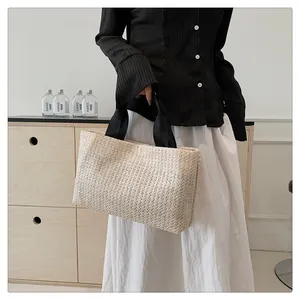 Detailed view of woven straw tote bag featuring contrast black fabric handles