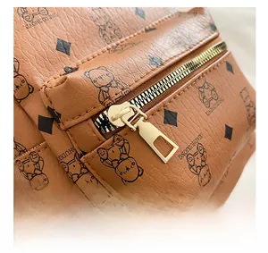 Detailed close-up of smooth gold zipper on brown PU leather backpack with bear pattern