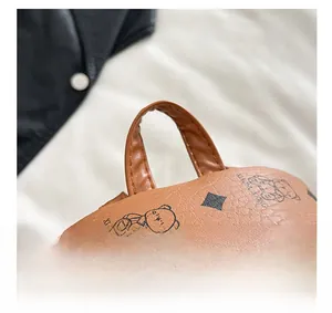 Detail of brown pebbled leather bag featuring bear print and smooth metal zipper closure