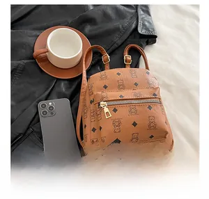 Brown PU leather mini backpack with bear print shown next to a smartphone for size scale