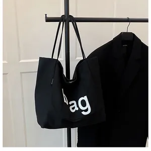 Gros plan sur le sac fourre-tout en toile noire avec lettrage artistique et étiquette mode