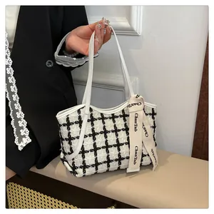 Detail einer schwarz-weiß karierten Tweed-Tasche mit elegantem Seidenband-Detail