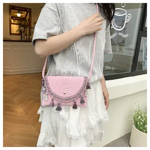 Detail of pink woven saddle bag with colorful tassels held by a model in a cafe setting