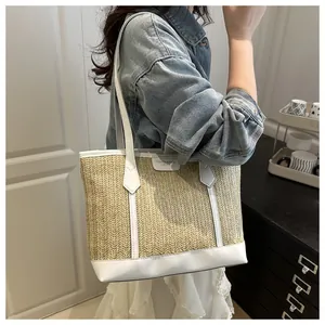 Détail du sac cabas en paille beige avec finitions en cuir blanc et écusson logo