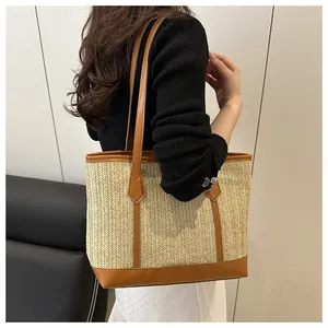 Détail d'un grand sac cabas en paille avec bordure en cuir marron porté par un mannequin