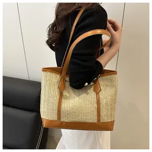 Vue détaillée du sac cabas en paille tissée avec anses en cuir brun et texture beige