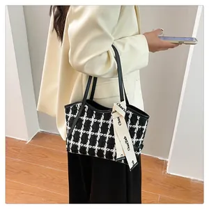 Detail der schwarz-weißen Tweed-Einkaufstasche mit elegantem Zierband und Textur