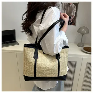 Détail de la texture en paille tressée en V et des bordures en cuir noir d'un grand sac