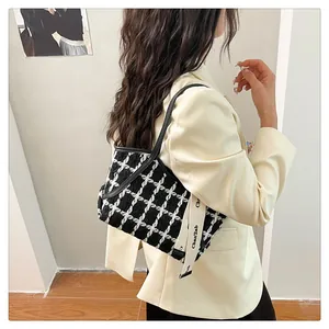 Detail der karierten Tweed-Schultertasche mit Logo-Gurt auf einem beigen Anzug