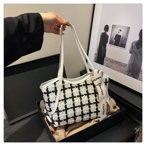 Detail der Tweed-Tasche mit Karomuster, Lederriemen und Seidenband in Geschenkbox