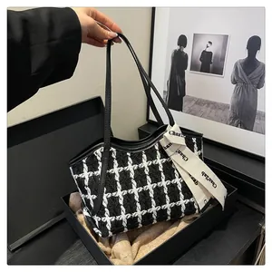 Detaillierte Makroansicht der Tweed-Textur und des Logo-Bandes an der schwarzen Tasche