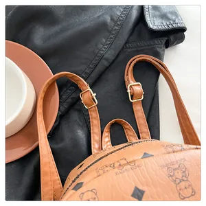 Détail du sac à dos en cuir caramel avec motifs d'ours et boucles métalliques dorées