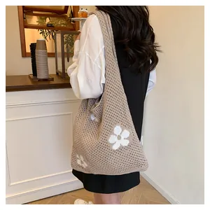 Detailaufnahme einer Häkel-Tragetasche mit weißen Blumenmustern und Mesh-Hohlstruktur