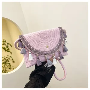 Detail of light pink woven saddle bag featuring ethnic tassels and intricate braided lace
