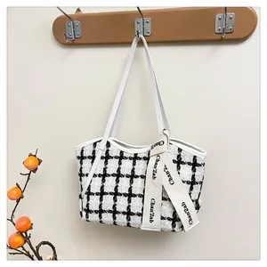 Nahaufnahme der schwarz-weißen Tweed-Tasche mit dekorativem Logo-Band und Lederriemen