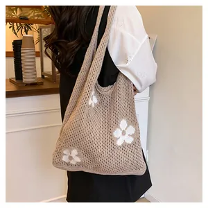 Detailansicht einer khakifarbenen Häkeltasche mit weißen Blumenmustern und Netzstruktur