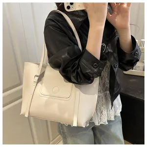Close-up of cream leather tote bag with silver buckle worn with casual denim outfit