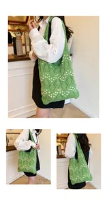 Detail of green crochet tote bag with white pearl accents and wide shoulder strap
