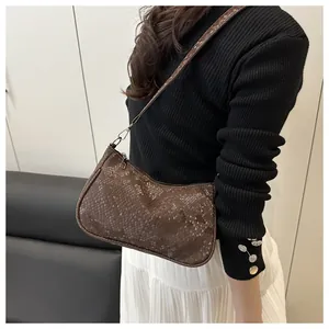 Detail of dark brown snake-print crossbody bag with leather texture and zip closure
