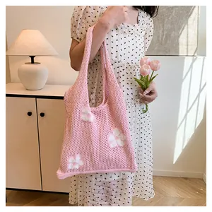 Detaillierte Nahaufnahme einer rosa Häkeltasche mit weißen Blumenmustern und Stricktextur