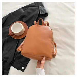 Détail d'un sac à dos marron en cuir PU avec motifs sur un fond en tissu beige