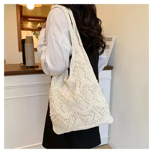 Detail of cream crochet tote bag featuring intricate openwork and white pearl accents
