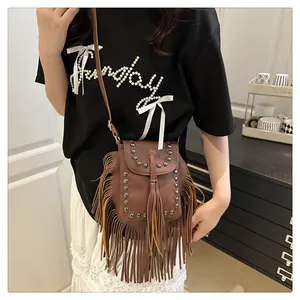 Détail d'un sac bandoulière en cuir marron avec franges bohèmes et rivets métalliques