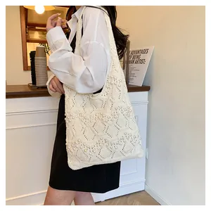 Detail of cream white knit tote bag with delicate pearl embellishments and woven texture