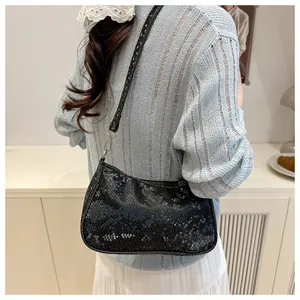 Detail of black snake-pattern underarm bag with scale texture and silver hardware on model