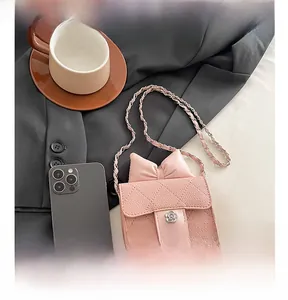 Rosa Mini-Stepptasche mit Schleife und Blumenschnalle neben einem Smartphone-Vergleich