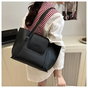 Detail view of a black faux leather tote bag with adjustable straps on a shoulder