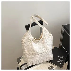 Détail du sac cabas en dentelle crochetée avec texture florale sur une valise