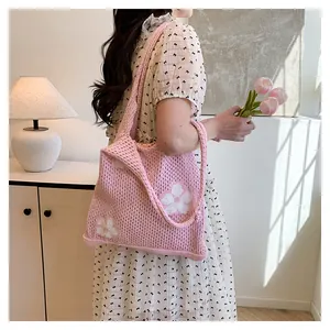 Detail der Strickstruktur und des weißen Blumendesigns dieser rosa Netztasche