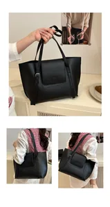 Detail of a large black leather tote bag with adjustable straps and round embossed design