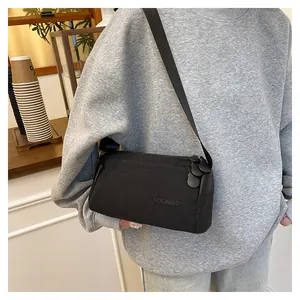 Detail van een zwarte nylon crossbodytas met drie ritsen en verstelbare schouderriem