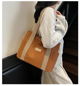 Dettaglio di una borsa tote in tela marrone con spalline crema ed etichetta moda