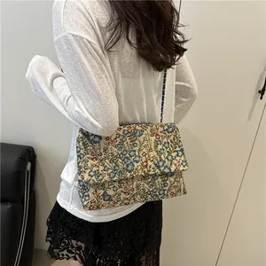 Floral jacquard shoulder bag with metal chain strap shown on model in minimalist setting
