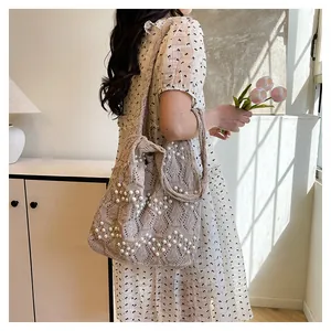 Detailed view of beige crochet tote bag with elegant white pearl V-shape patterns