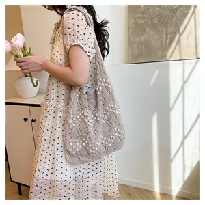 Détail du sac cabas en tricot avec motif au crochet et décorations en perles blanches