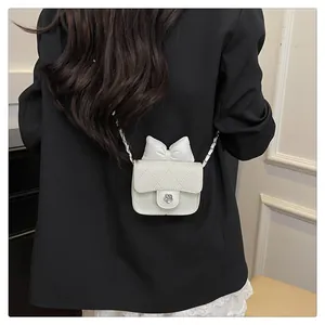 Detail der weißen Stepptasche mit 3D-Schleife und silbernem Schloss in Blumenform