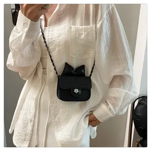 Schwarze Mini-Umhängetasche mit Schleife und Kettenriemen am Model in Nahaufnahme