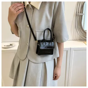 Mini black crocodile pattern leather handbag shown on model with gold hardware detail