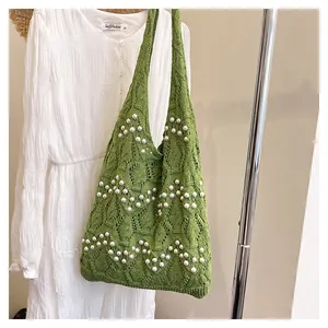 Détails d'un sac cabas en tricot vert avec motifs losanges et perles blanches