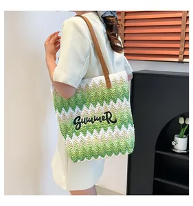 Detail of hand-woven straw beach bag with green wave patterns and Summer embroidery