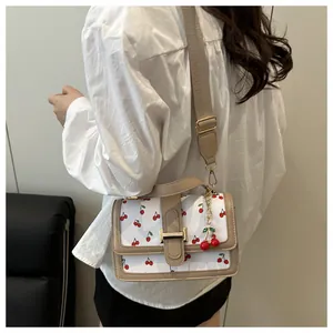 Detail view of cherry print crossbody bag with khaki trim and stylish wide strap