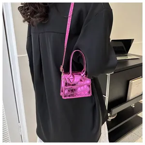 Mini glossy crocodile pattern shoulder bag in fuchsia pink shown as a crossbody wear