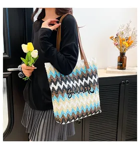 Detailed view of the wave pattern straw tote bag with black Summer embroidery and leather strap